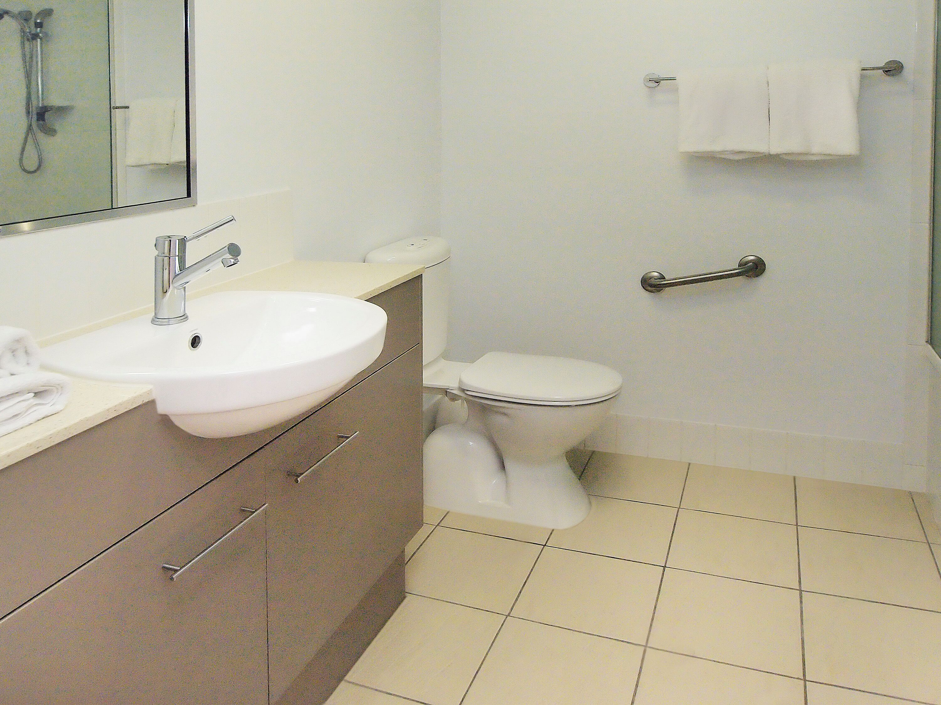 Een badkamer met een witte wastafel, toilet en douche.