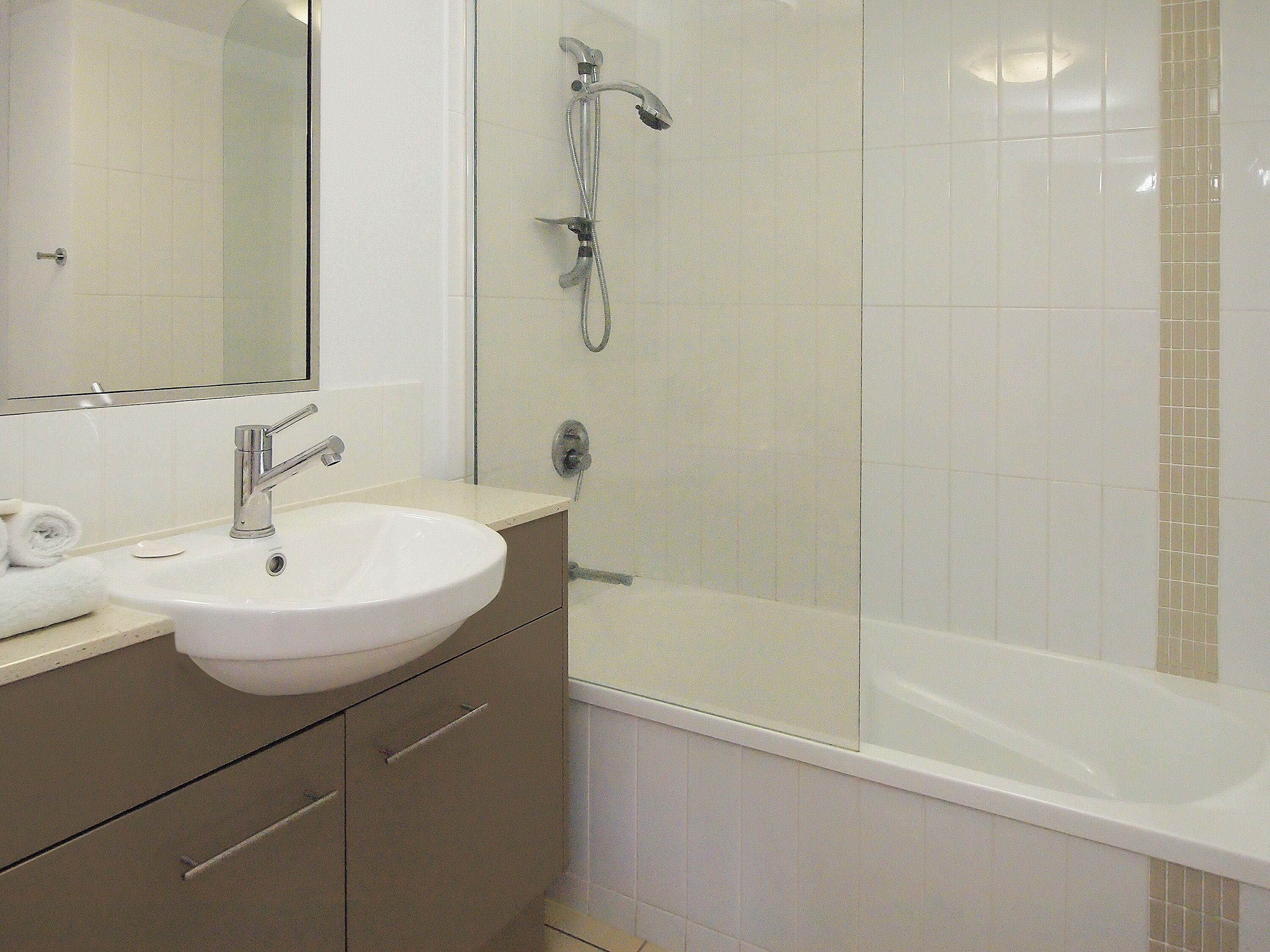 Ein Badezimmer mit Waschbecken, Spiegel und Dusche.