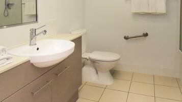 Une salle de bain équipée d’un lavabo, d’un miroir, de toilettes et d’un espace douche.