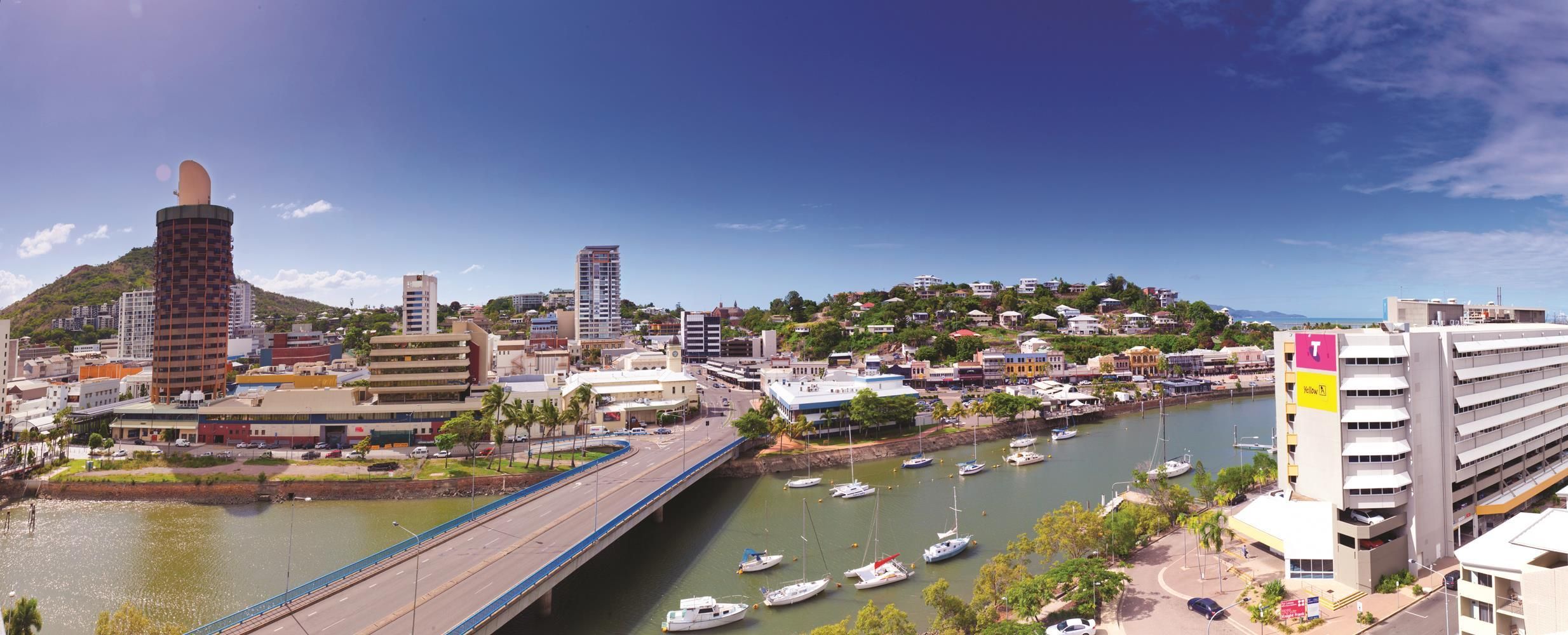 A coastal cityscape with a bridge, marina, and buildings.