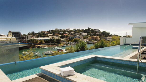 Una piscina con vistas a un puerto deportivo y edificios en la colina.