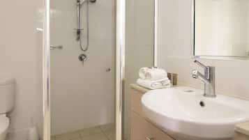 Une salle de bain moderne avec une douche à parois de verre, un lavabo blanc et un miroir au-dessus.