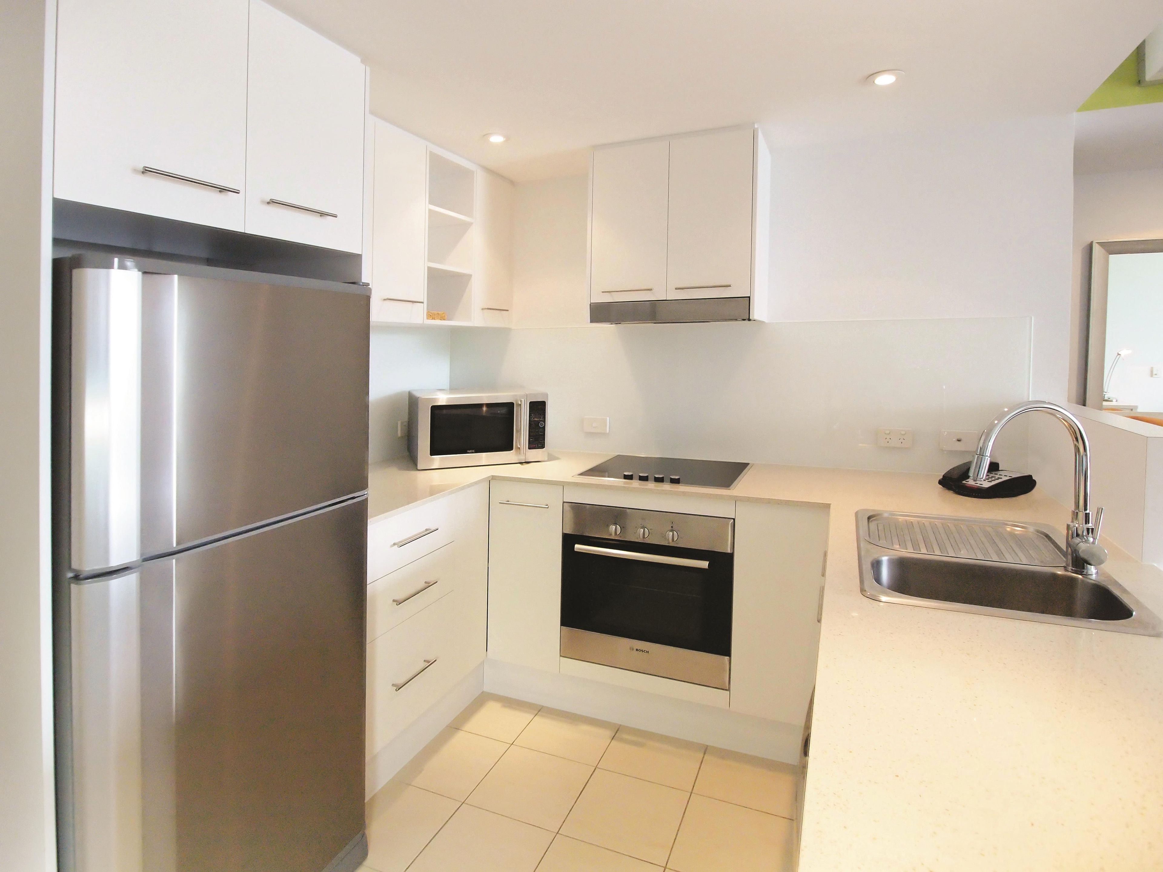 A modern kitchen with a stainless steel refrigerator, a microwave, an oven, and a sink.