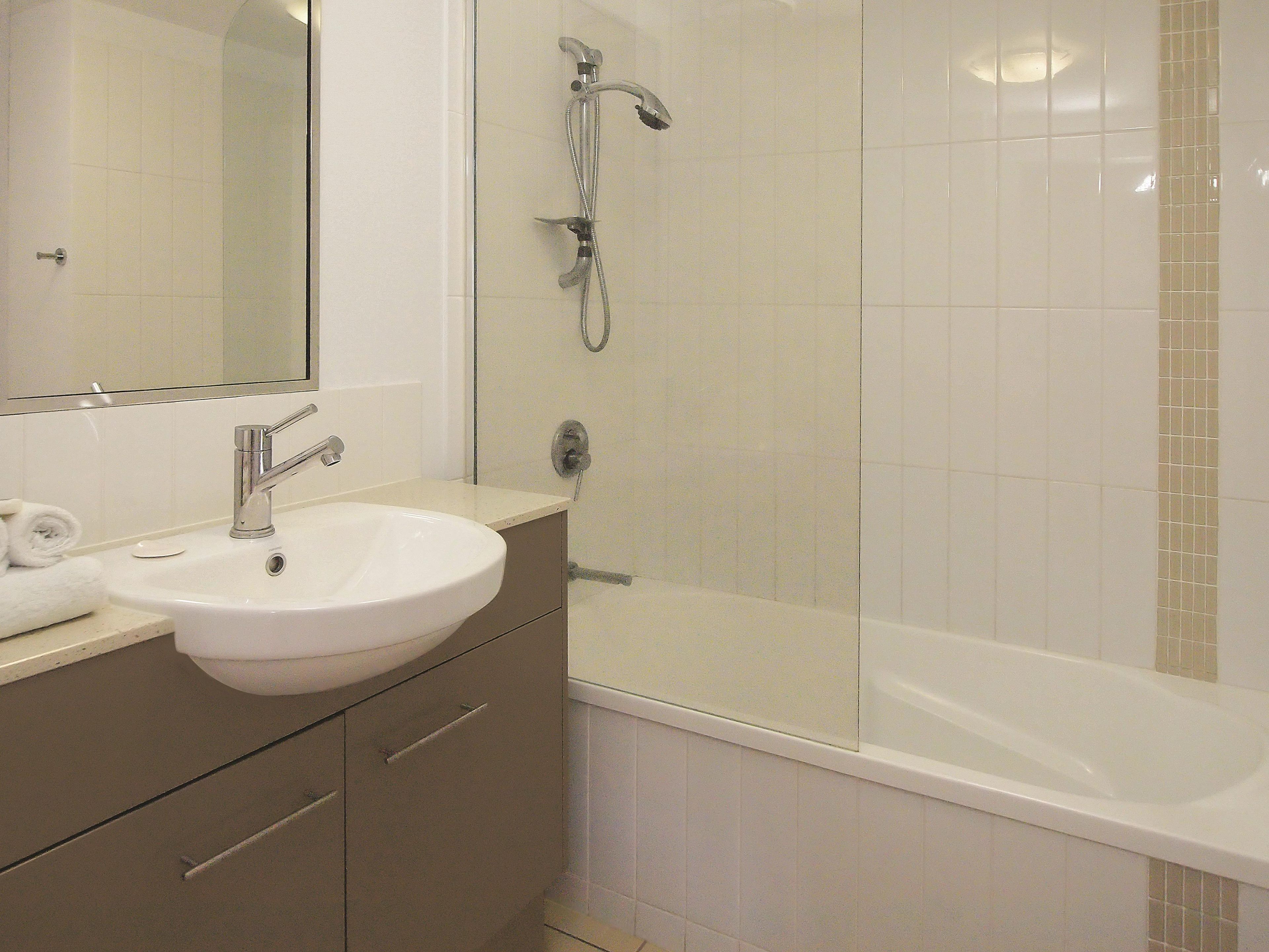 A bathroom with a white sink, a mirror, a shower, and a bathtub.