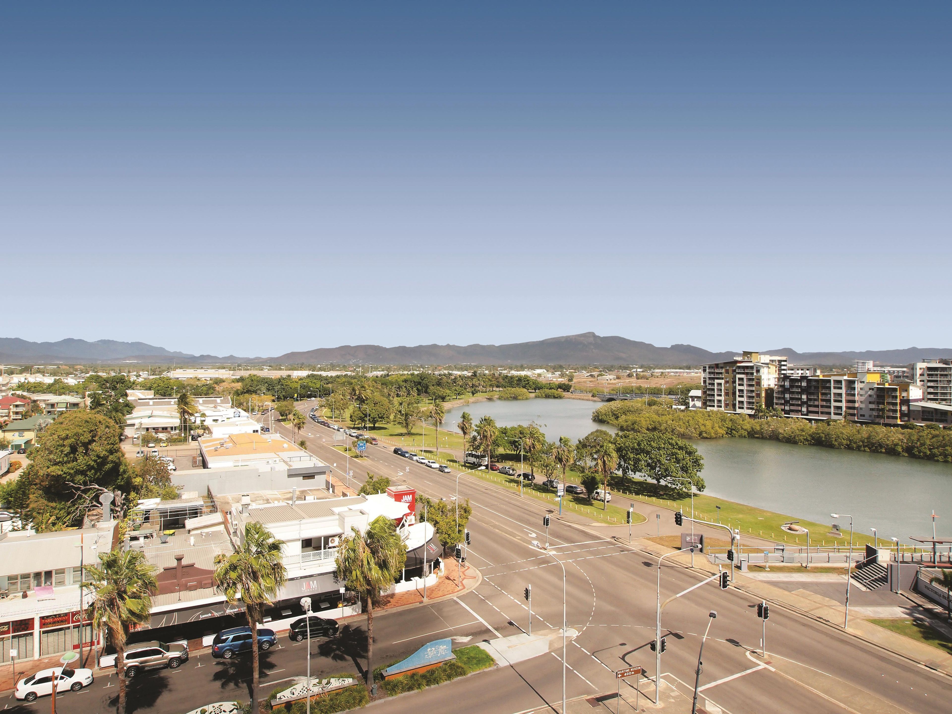 A cityscape with a river, buildings, and a mountain range in the background.