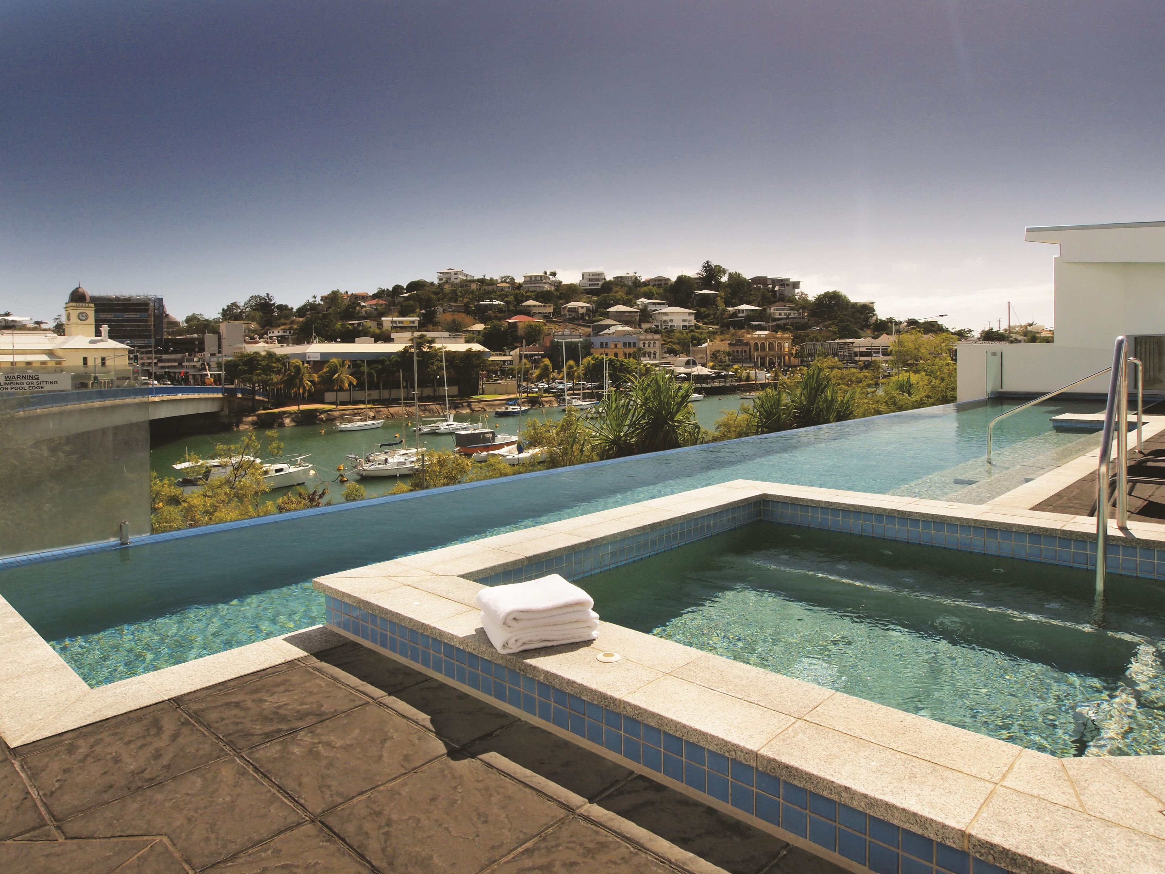 A swimming pool with a view of a marina and buildings in the background.