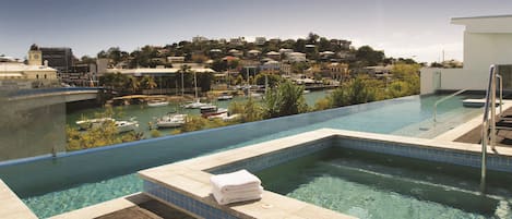 A swimming pool with a view of a marina and buildings in the background.