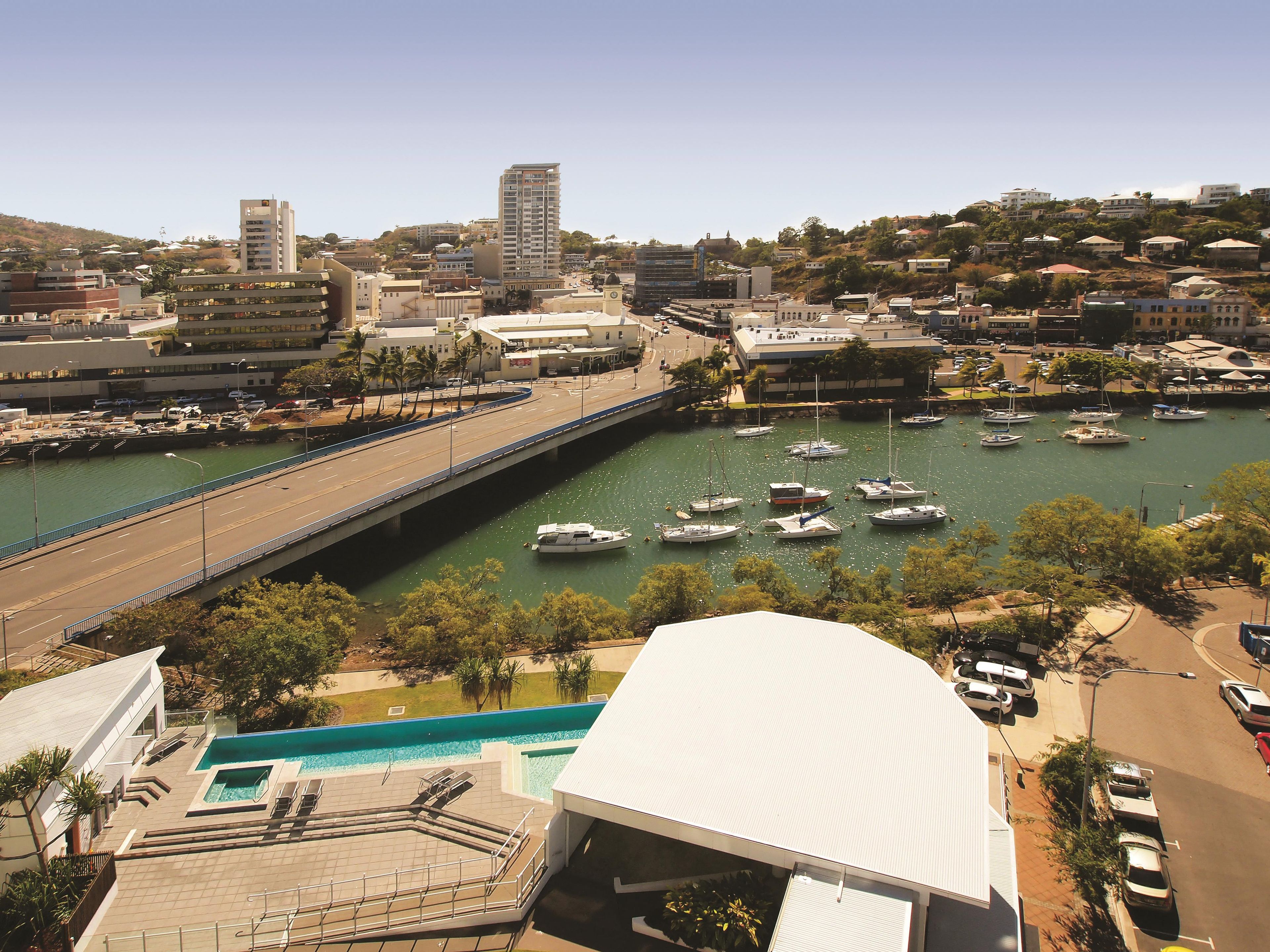 A marina with boats, a bridge, and buildings in the background.