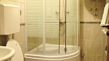 Une salle de bain avec une douche à parois de verre, des toilettes et un radiateur fixé au mur.