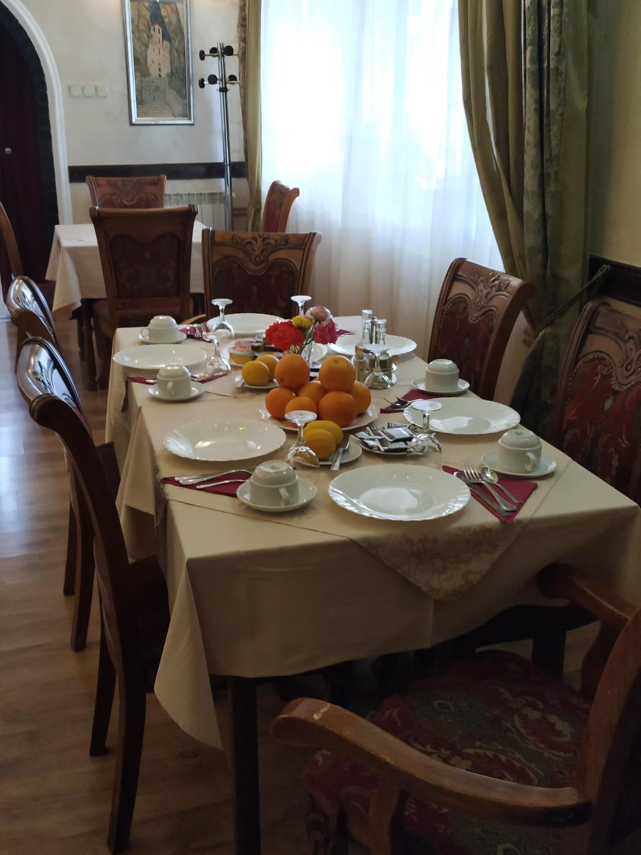 A dining room with a long table set for a meal, surrounded by wooden chairs.