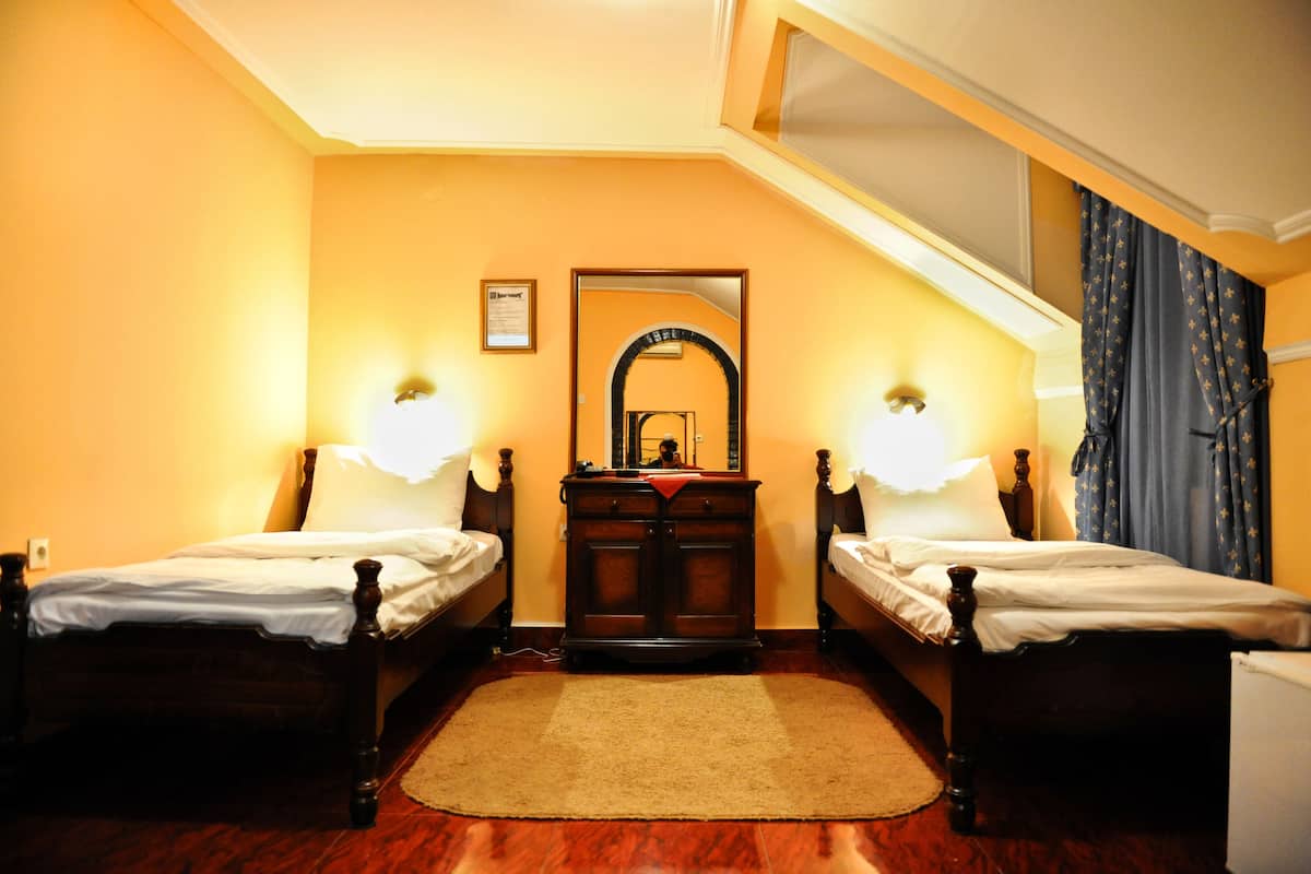 A room with two wooden beds, a mirror, and a dresser.
