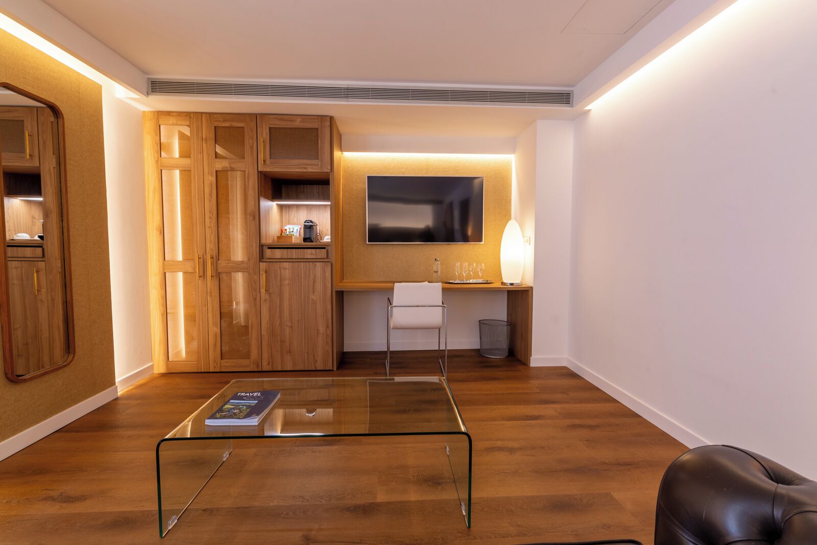 Una sala moderna con armarios de madera, una mesa de centro de vidrio, un sofá y un televisor.