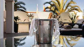 Una copa de champán sobre una mesa reflectante, con vista a palmeras y un rincón de estar acogedor al fondo.