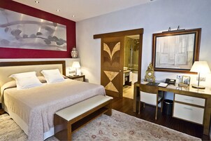 A hotel room with a bed, bedside tables, a desk, and a mirror.