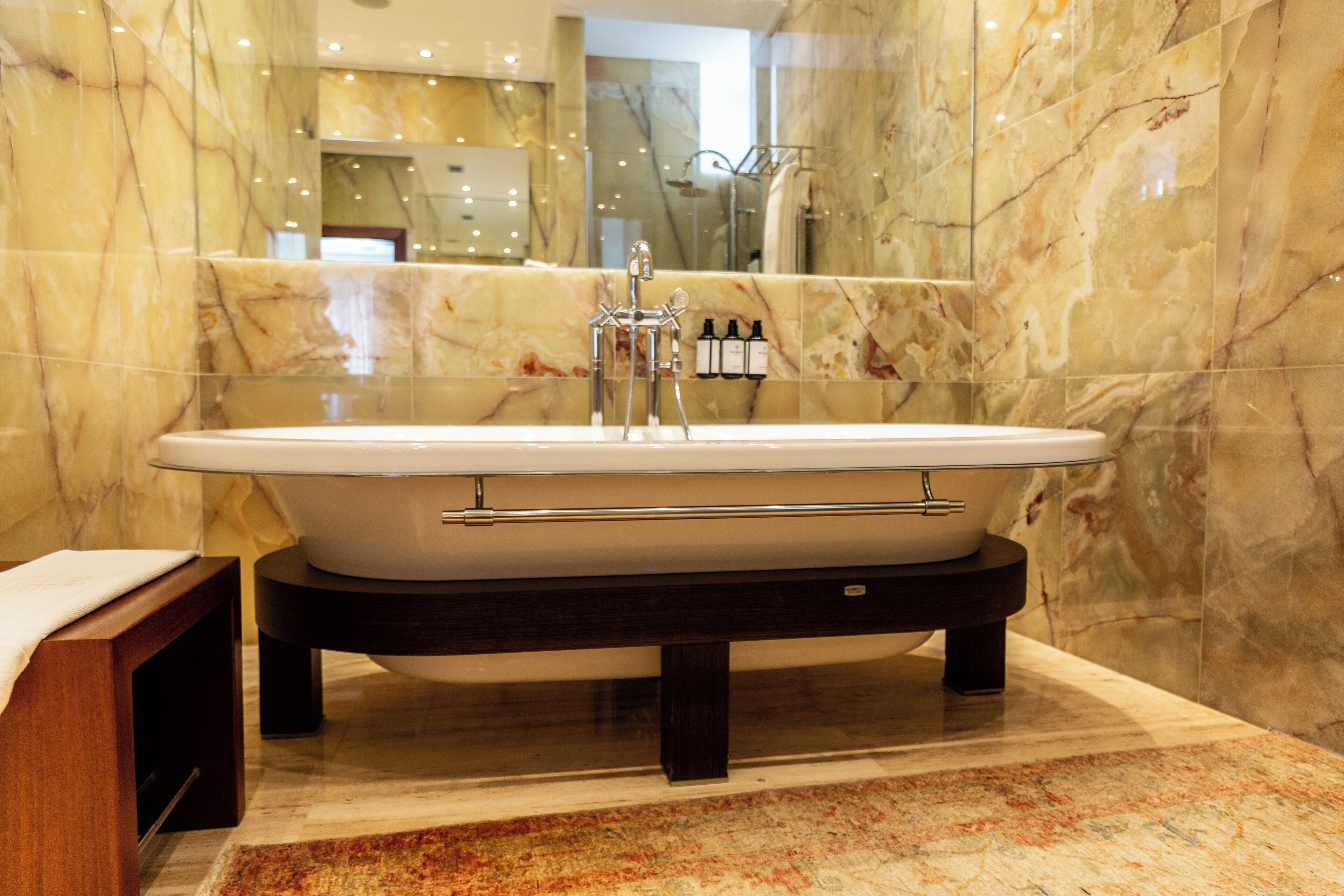 A modern bathroom with a freestanding bathtub, marble walls, and a glass shower enclosure.