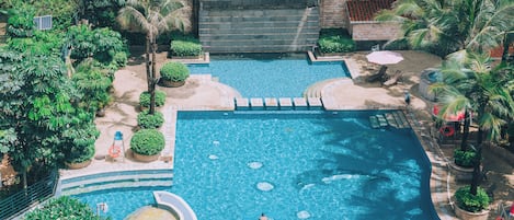 Una piscina techada, una piscina al aire libre, sombrillas