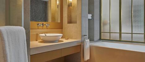 A modern bathroom with a large bathtub, a white sink, and a large mirror.