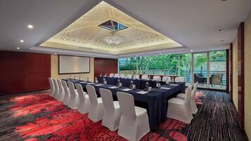 A conference room with a high ceiling, a large chandelier, and a red carpeted floor.