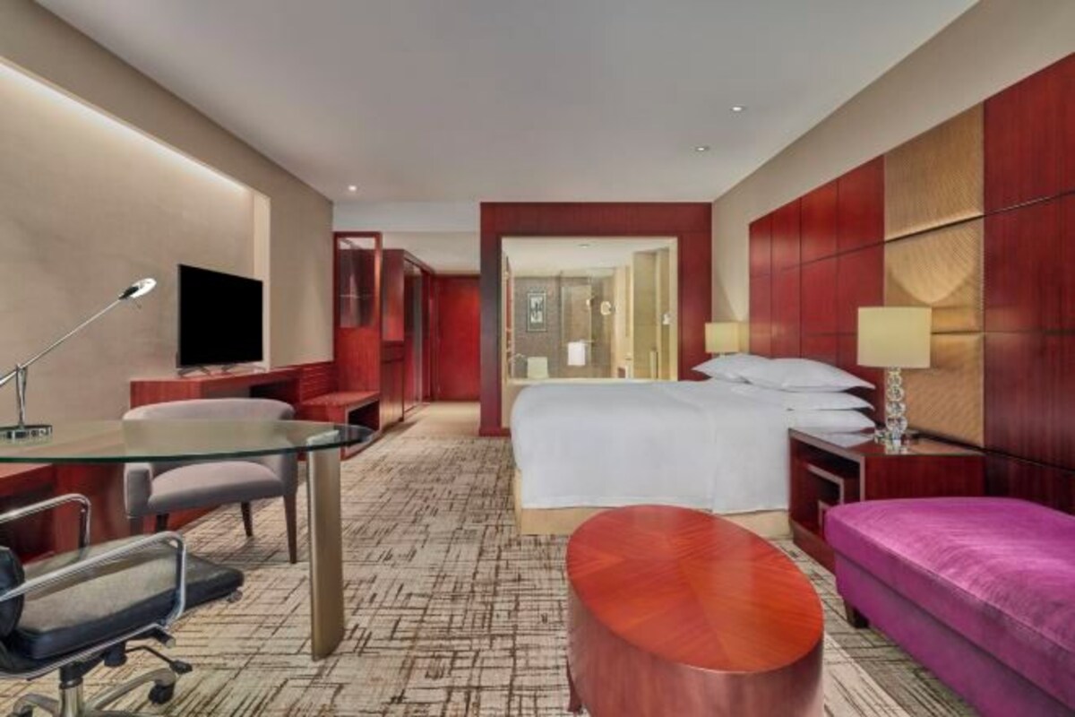 Una habitación de hotel con una cama, un escritorio con silla, un sofá y un televisor.