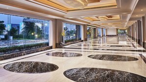 Un vestíbulo amplio con piso de mármol, ventanas grandes y un candelabro imponente.