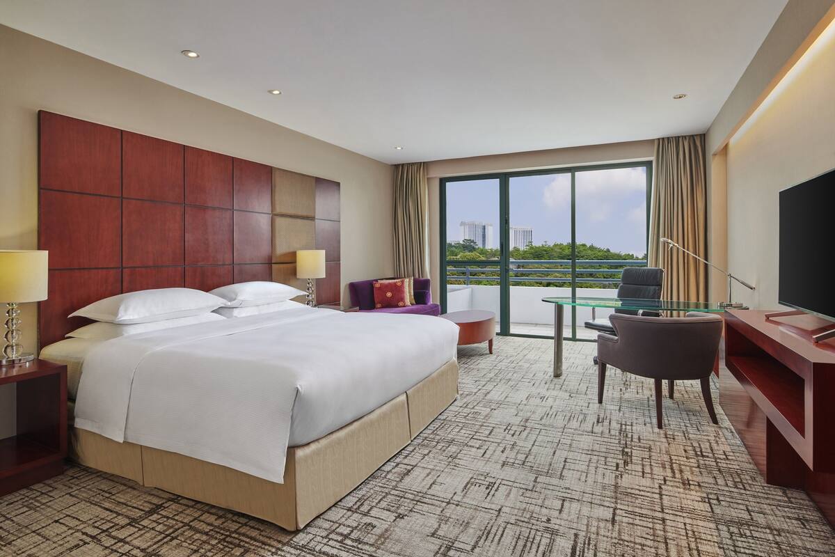 Une chambre d’hôtel avec un grand lit, un bureau, une chaise et un téléviseur.