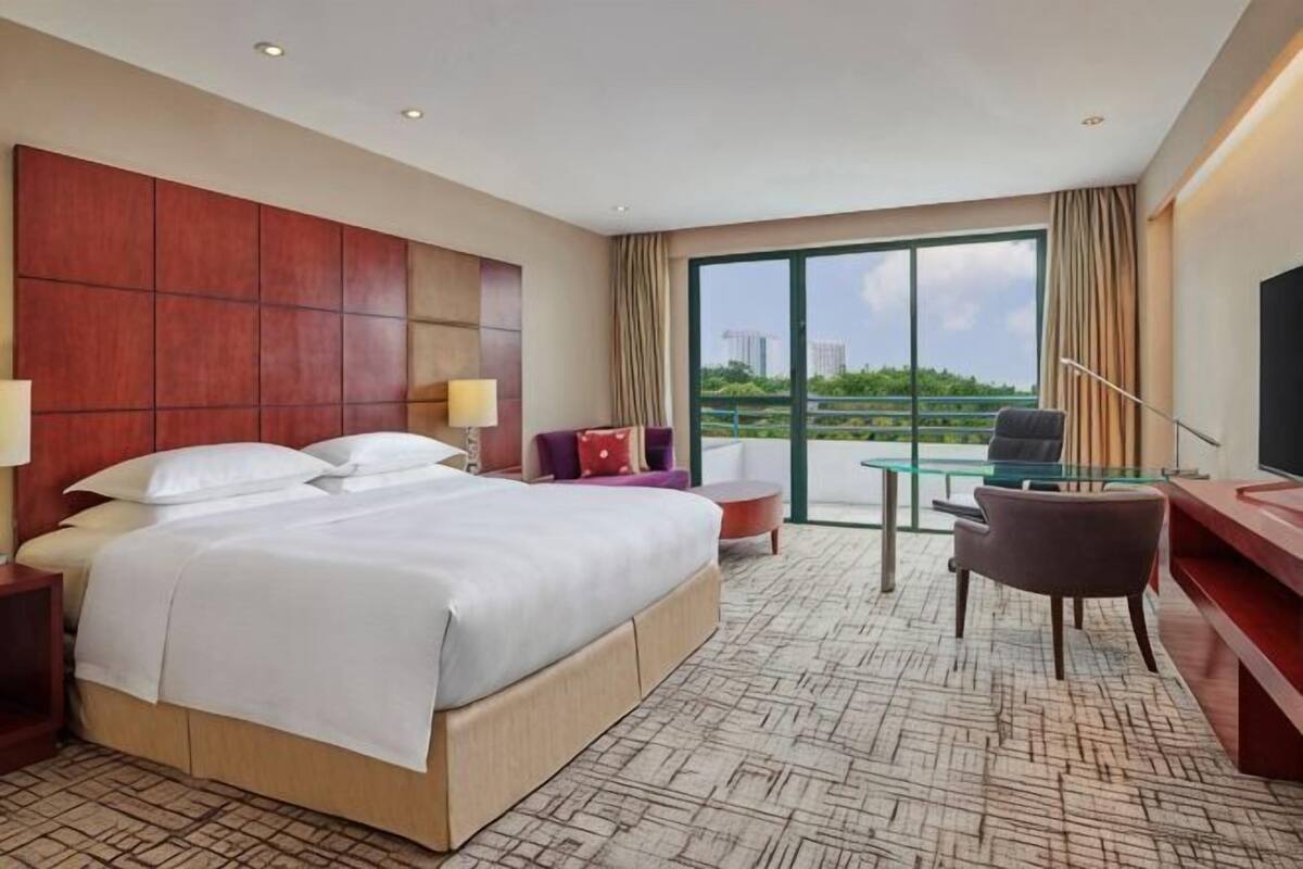 Une chambre d’hôtel avec un grand lit, un bureau, une chaise, une télévision et un balcon avec vue.