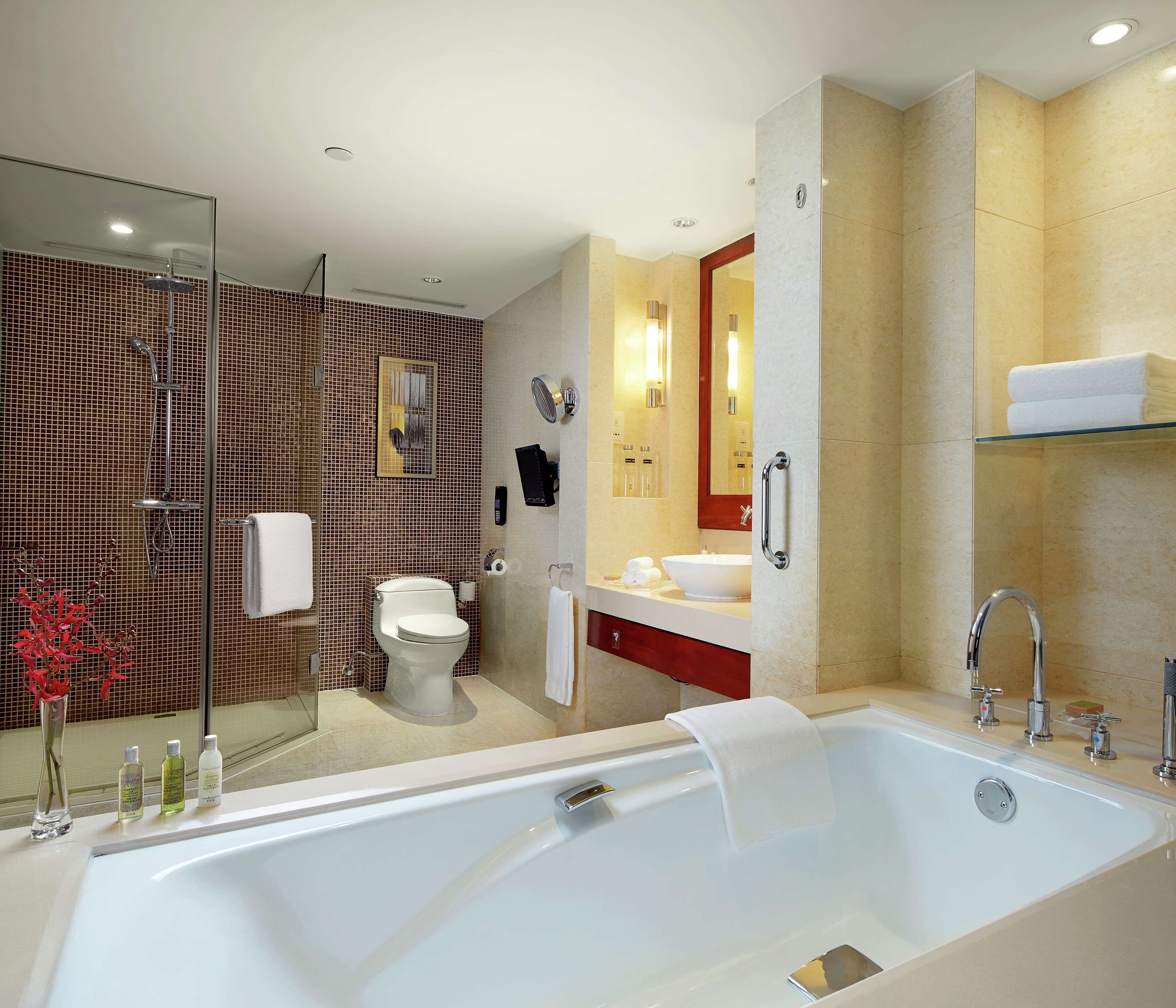 Een moderne badkamer met een groot bad, douche, toilet en wastafel.