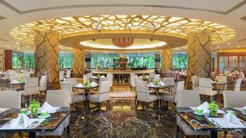 A modern restaurant with a central bar, marble flooring, and a unique ceiling design.