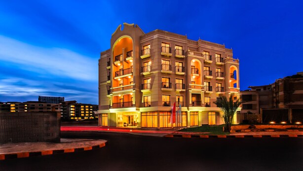 A multi-story hotel with a prominent entrance, balconies, and a well-lit facade.