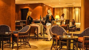 A hotel lobby with wicker furniture, a bar area, and a seating area with a sofa and chairs.