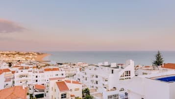 Un pueblo costero con edificios blancos y techos de tejas rojas, una playa y una vista despejada del mar.