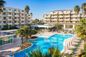 Una piscina techada, una piscina al aire libre, sombrillas