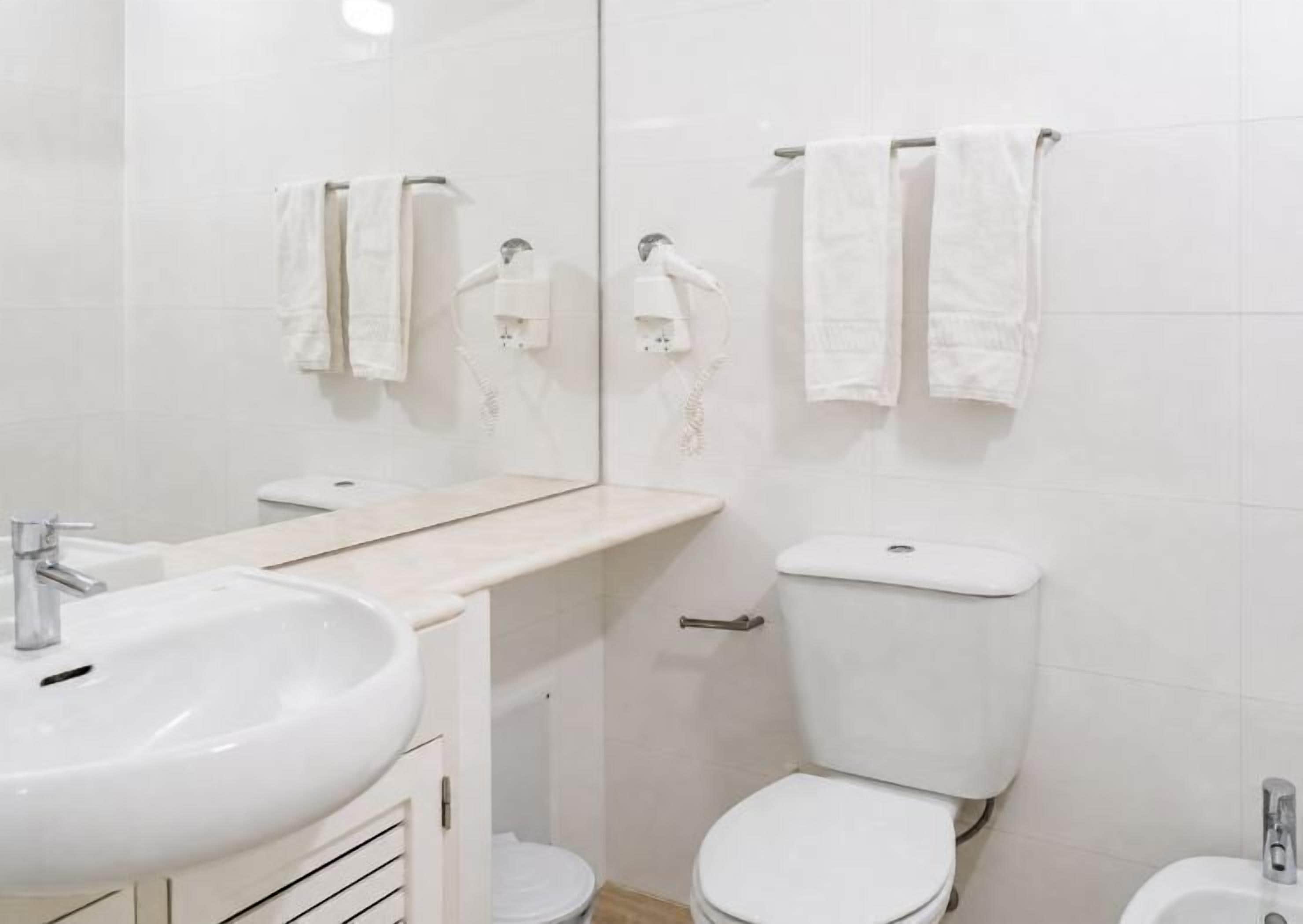 Un baño con lavabo, inodoro y toalleros.