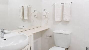 Un baño con lavabo, inodoro y toalleros.