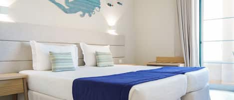 A hotel room with two beds, a large window, and a wall mural.