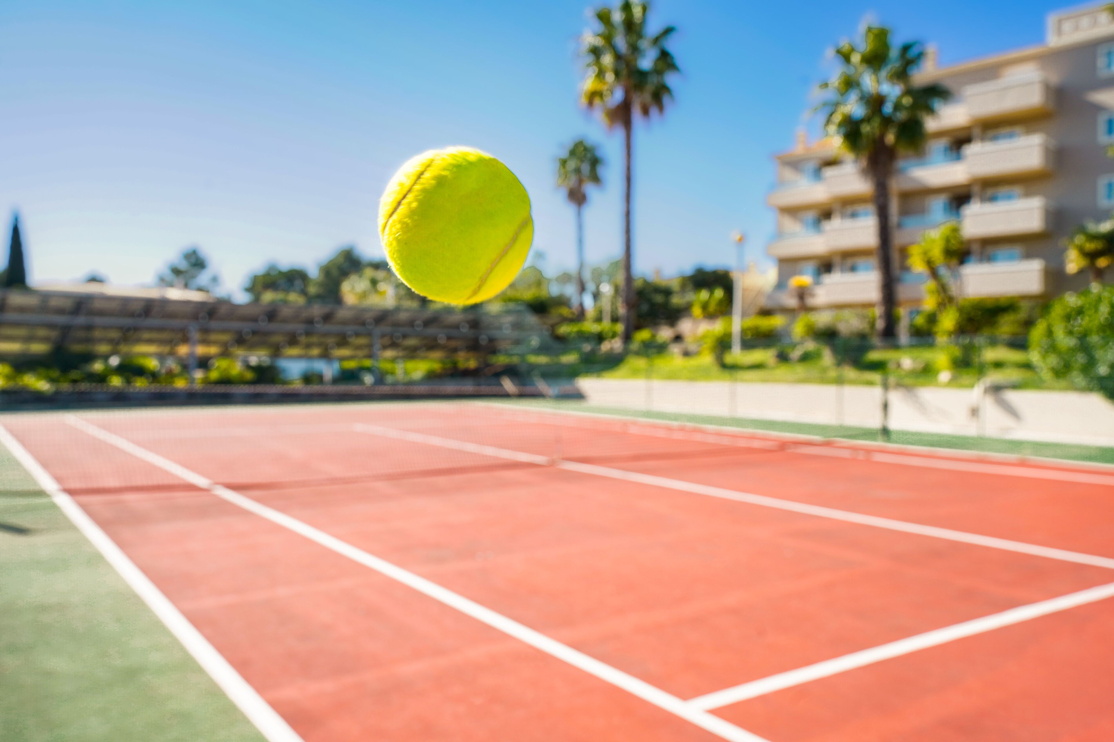 A tennis court with a net in the foreground and a building in the background.