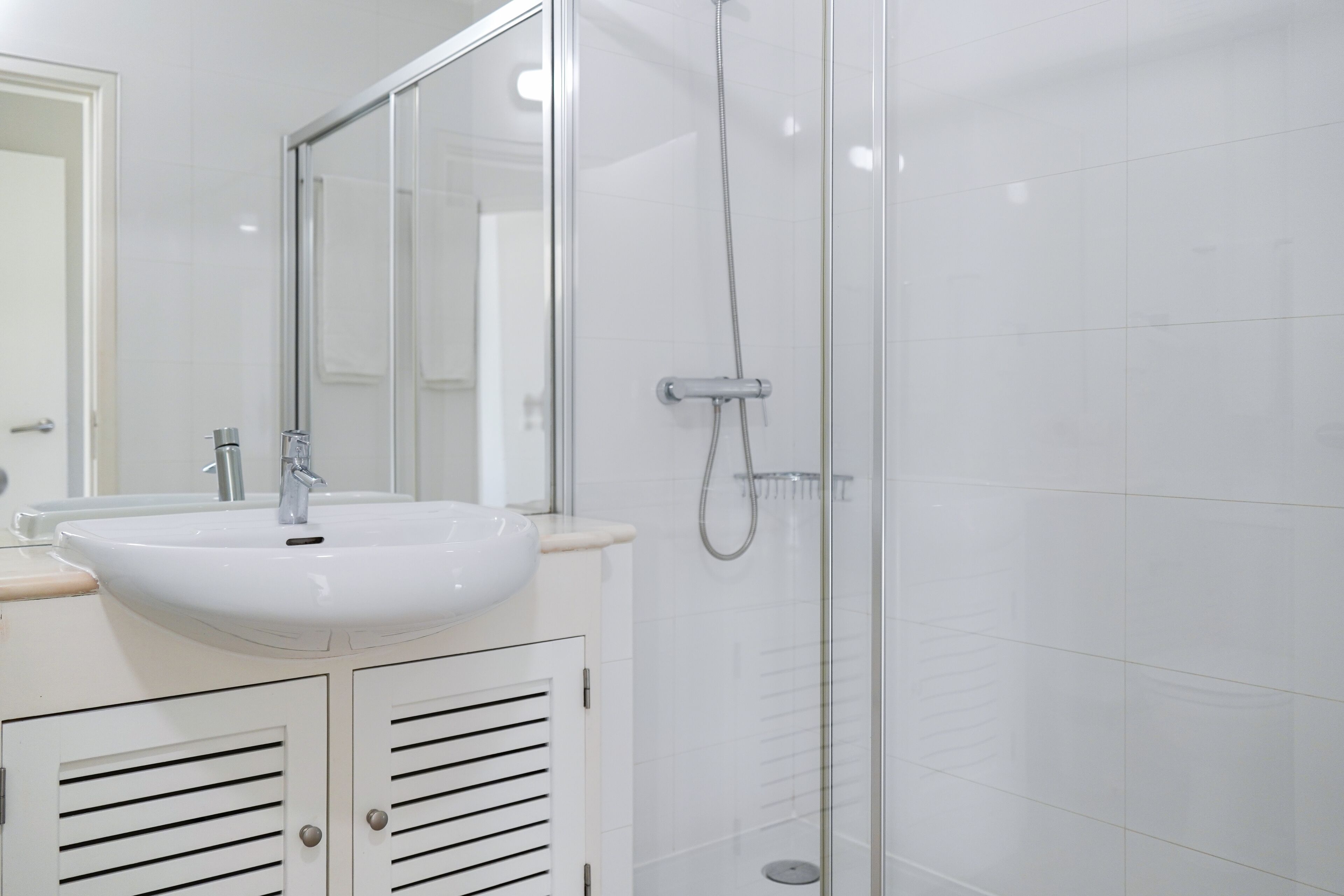 A bathroom with a white sink, mirror, and glass shower enclosure.