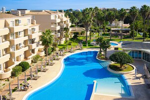 Una piscina techada, una piscina al aire libre, sombrillas