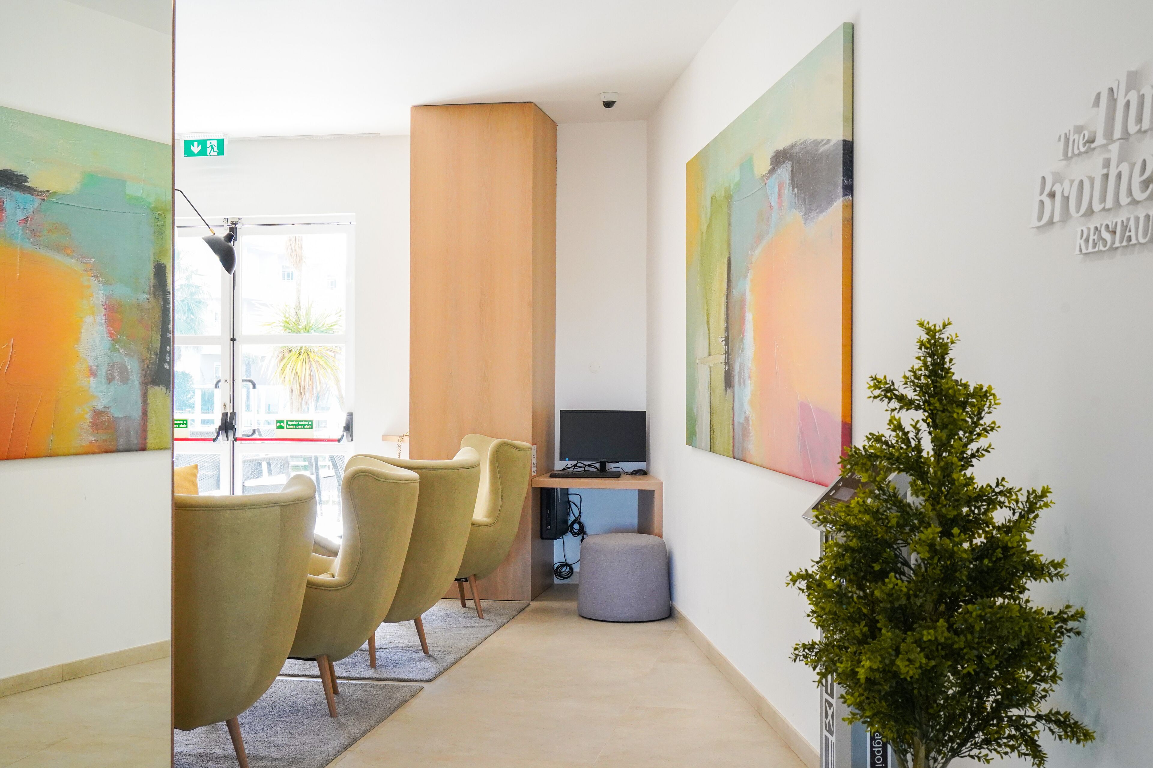 A modern office space with a desk, chairs, a television, and artwork on the walls.