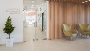 A reception area with a glass door leading to a restaurant, two yellow chairs, and a potted plant. - Vitors Plaza (Portimão)