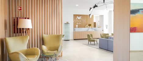 A modern lobby with two armchairs, a reception desk, and a seating area.