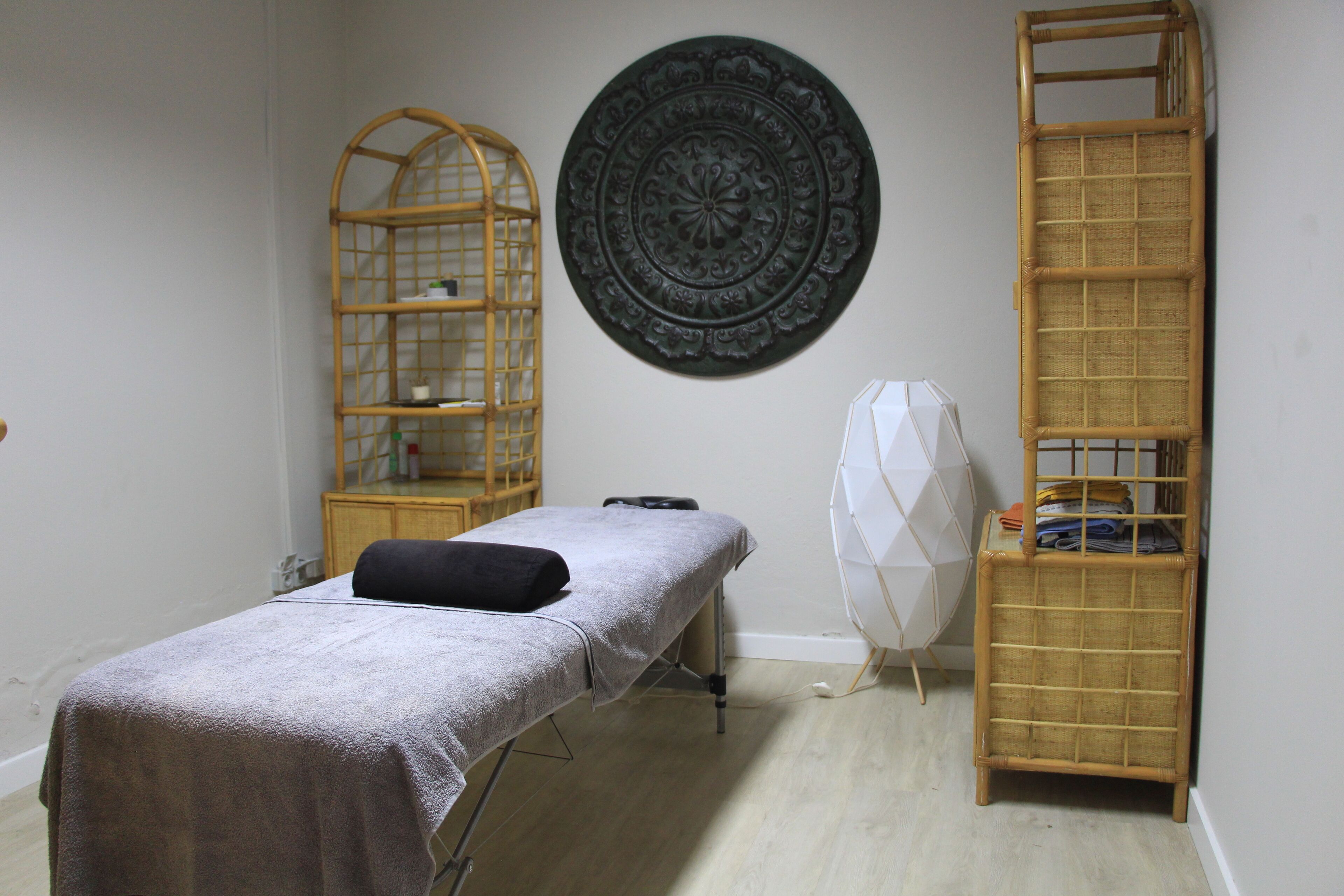 A room with a massage table, a wooden shelf unit, and a decorative wall plate.