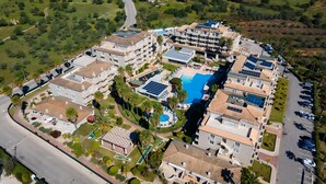 An aerial view of a resort with multiple buildings, a central swimming pool, and a parking area. - Vitors Plaza (Portimão)