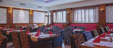A conference room with multiple tables and chairs, equipped with nameplates and table settings.