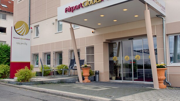 The exterior of Airport Global Hotel with a clear entrance, a signboard, and a few potted plants. - Airport Global Hotel  (Moerfelden-Walldorf)
