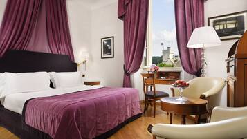 A hotel room with a bed, a desk, a chair, and a view of the city.