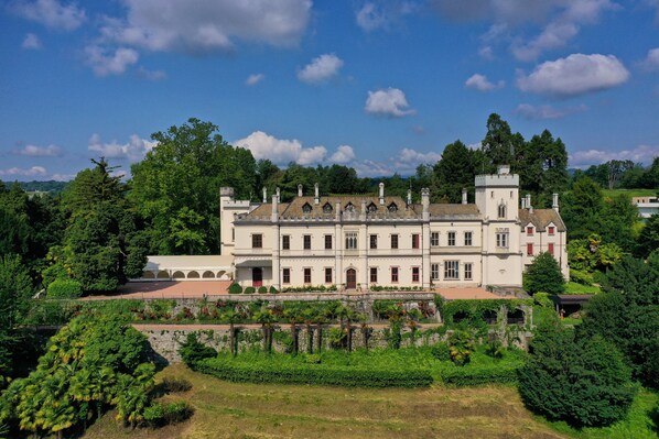 A large, historic building with multiple wings and a tower, surrounded by lush greenery and a well-maintained garden. - Castello Dal Pozzo Resort Lago Maggiore - Preferred Hotels & Resorts (Oleggio Castello)