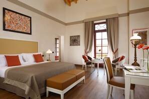A hotel room with a large bed, a sitting area with a table and chairs, and artwork on the walls. - Castello Dal Pozzo Resort Lago Maggiore - Preferred Hotels & Resorts (Oleggio Castello)
