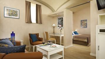 A modern hotel room with a living area, a dining table, a bed, and a TV.