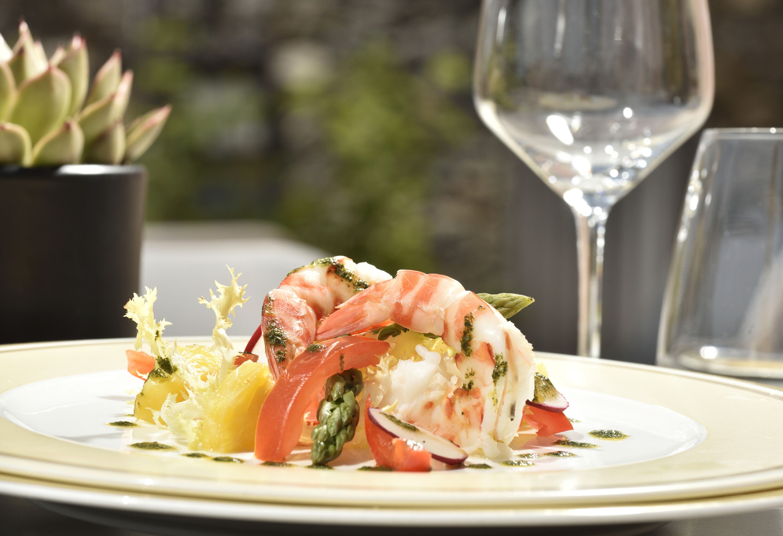 A plate of food with shrimp, vegetables, and a glass of wine.